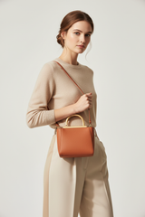 Female model holding Luxury Mini Shoulder Bag in Soft Terracotta