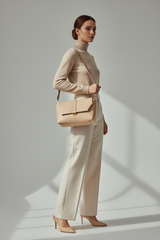 Female model carrying Sculpted Designer Shoulder Bag in Cream Beige