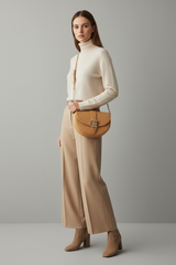 Female model carrying Curved Mini Shoulder Bag in Warm Sandstone