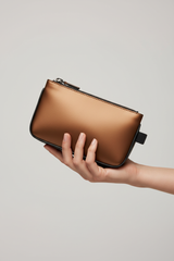Hand holding Minimal Luxe Pouch in Bronze and Black, portrait view