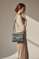 Female model carrying Contemporary Flap Shoulder Bag in Muted Teal