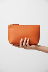 Hand holding Minimal Luxe Pouch in Orange and Gold, portrait view